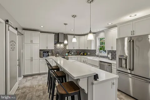 a kitchen with a dining table chairs sink and white cabinets