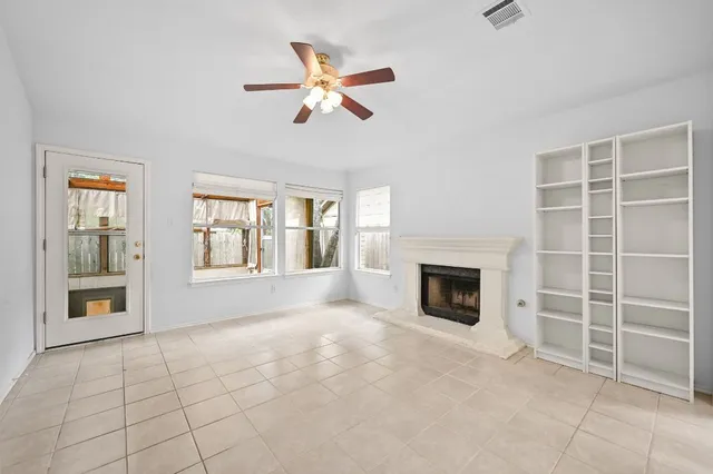 a view of an empty room with window and chandelier fan