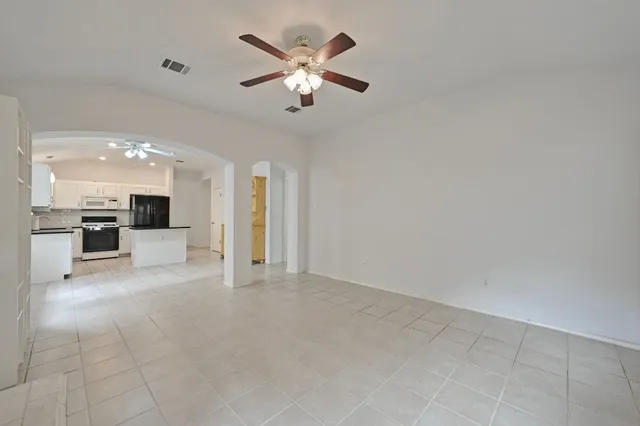 a view of a livingroom with a fireplace a ceiling fan and windows