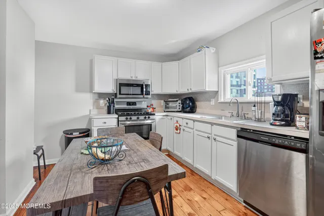 a kitchen with stainless steel appliances a table chairs and a refrigerator