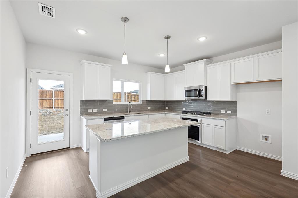 3900 Coco Lane Sherman, TX 75090 - Photo 2 of 40 Kitchen with appliances with stainless steel finishes, white cabinets, hanging light fixtures, a center island, and light stone counters