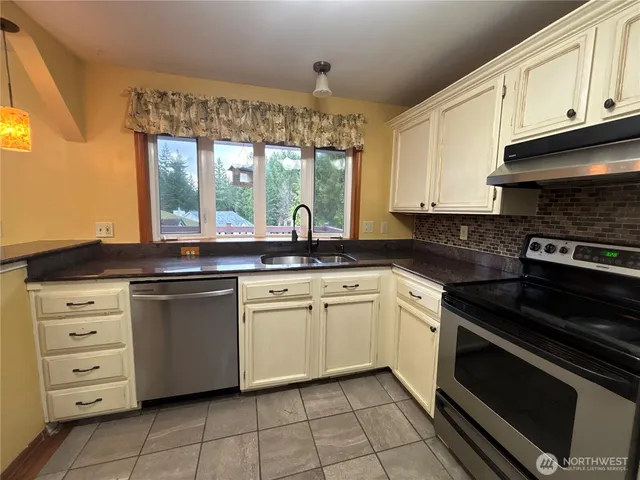 a kitchen with granite countertop white cabinets white appliances a sink and a window