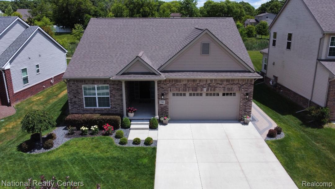 740 North Mill Street South Lyon, MI 48178 - Photo 1 of 56 Brick and siding exterior featuring a covered front entry with steps, an integrated two-car garage, a concrete driveway, and a paver walkway