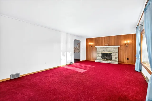 a view of empty room with floor to ceiling window and fireplace