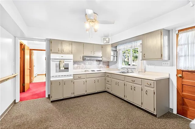 a kitchen that has a lot of white cabinets and stainless steel appliances