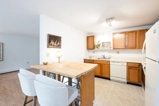 a kitchen with stainless steel appliances granite countertop a sink a stove a refrigerator a microwave oven with white cabinets and wooden floor