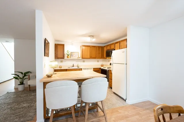 a kitchen with stainless steel appliances granite countertop a refrigerator a stove a sink dishwasher and white cabinets with wooden floor