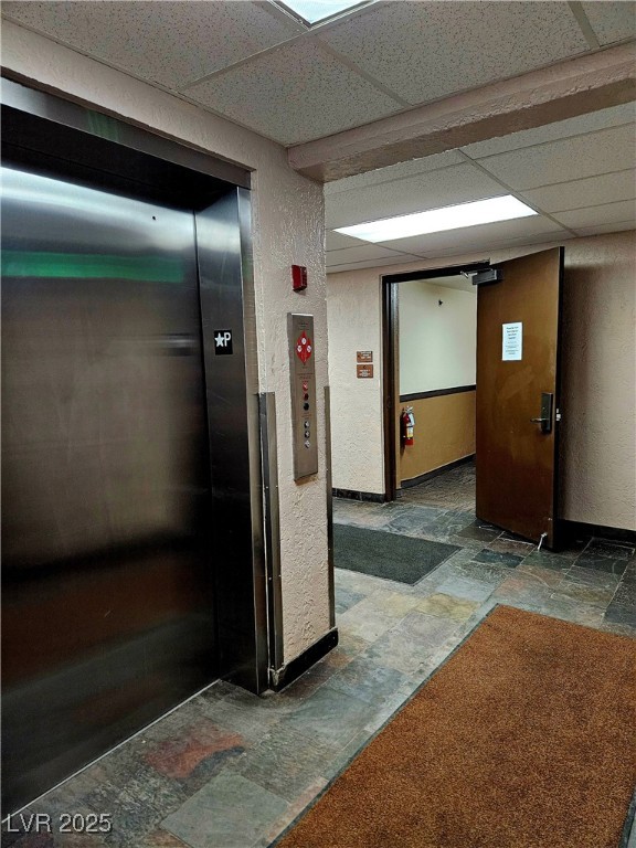 223 Hunter Ridge Drive, Unit 121 Brian Head, UT 84719 - Photo 29 of 35 Corridor featuring stone tile flooring, elevator, a textured wall, and a drop ceiling