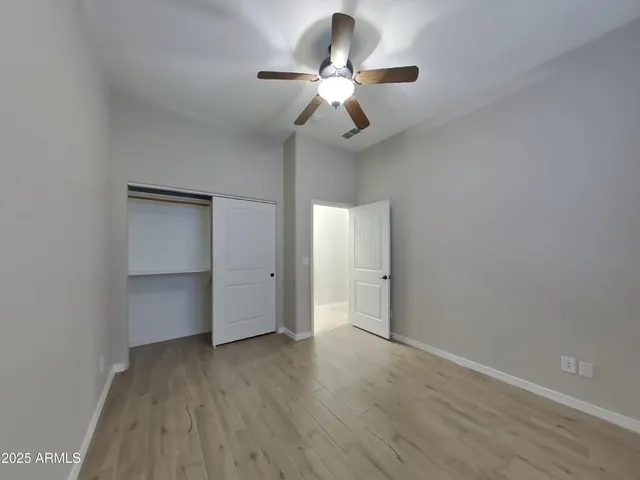 a view of empty room with wooden floor and fan