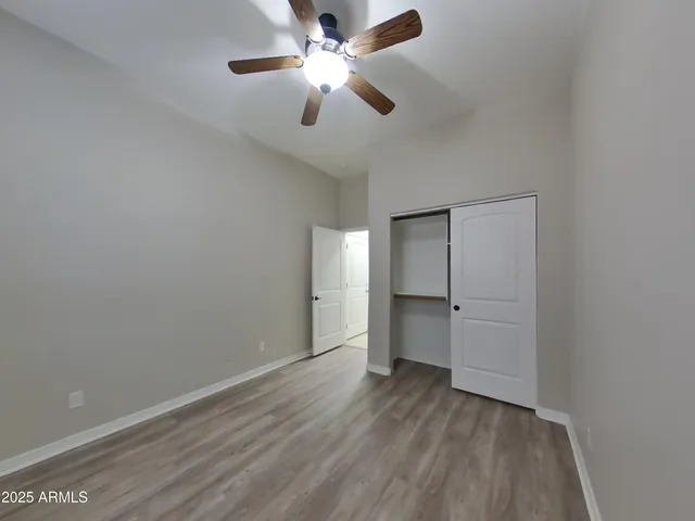 an empty room with wooden floor and ceiling fan