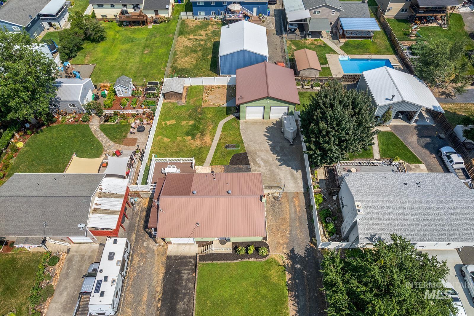 2007 Ripon Avenue Lewiston, ID 83501 - Photo 29 of 30 Aerial view showcasing a residential property with a brown metal roof, expansive paved driveway, and a detached two-car garage