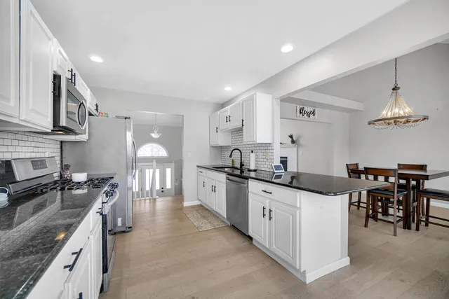 a large kitchen with stainless steel appliances granite countertop a stove a sink dishwasher and a refrigerator with wooden floor