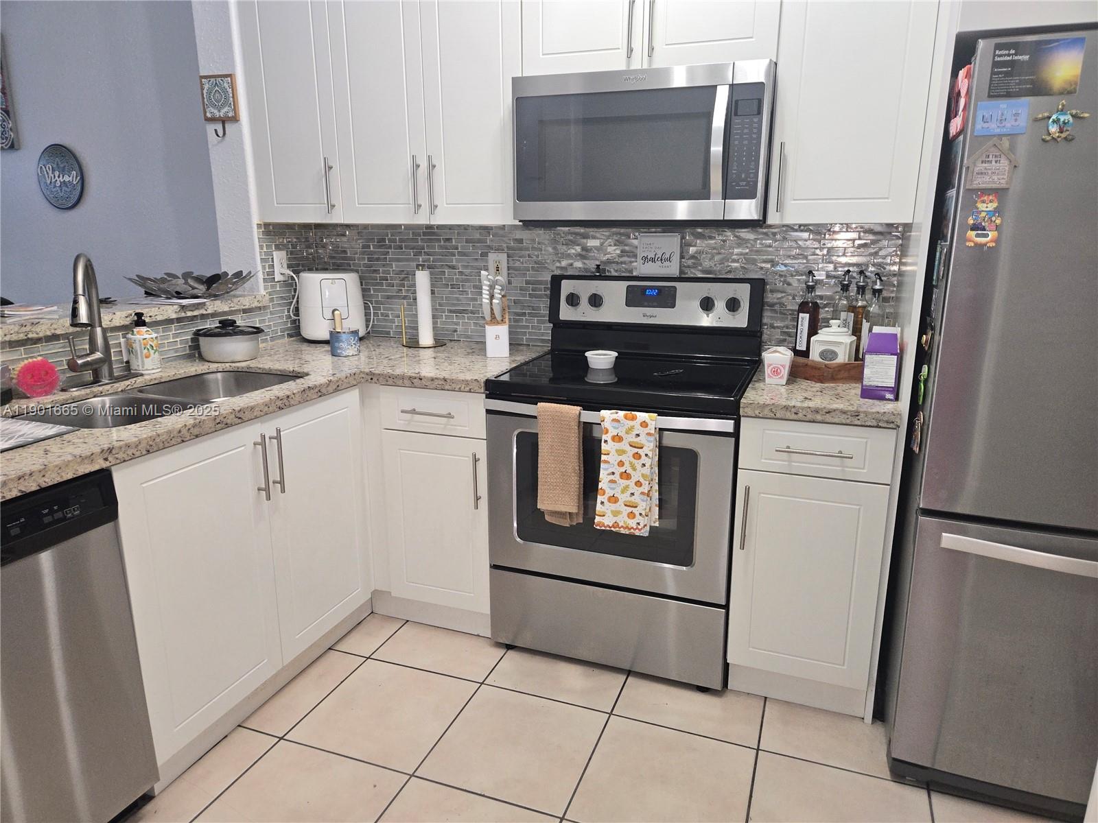 2731 Southeast 17th Avenue, Unit 100 Homestead, FL 33035 - Photo 3 of 12 a kitchen with stainless steel appliances granite countertop a stove microwave and refrigerator
