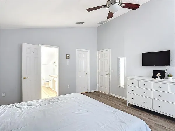 a bedroom with a bed and a flat tv screen on dresser
