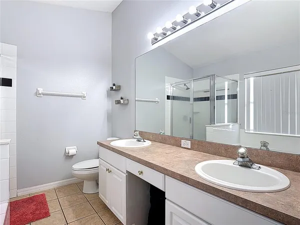 a bathroom with a granite countertop double vanity sink a mirror and a toilet