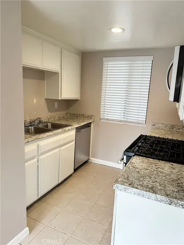 a kitchen with a stove a sink and white cabinets