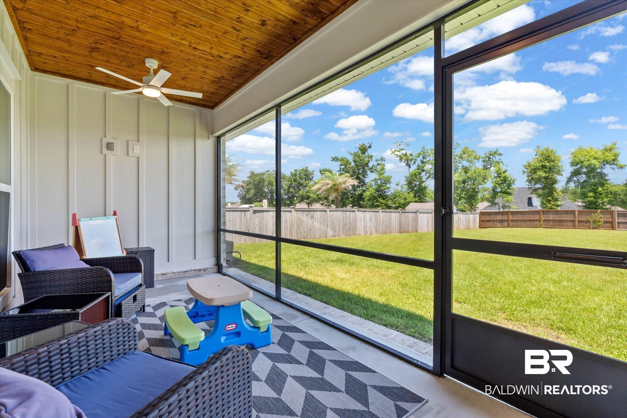 23523 Travis Stock Street Foley, AL 36535 - Photo 27 of 45 Screened porch featuring a natural wood-finish ceiling, a ceiling fan, white vertical paneling, concrete flooring, and an expansive fenced yard
