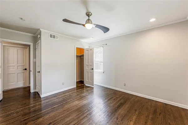 an empty room with wooden floor a ceiling fan and windows