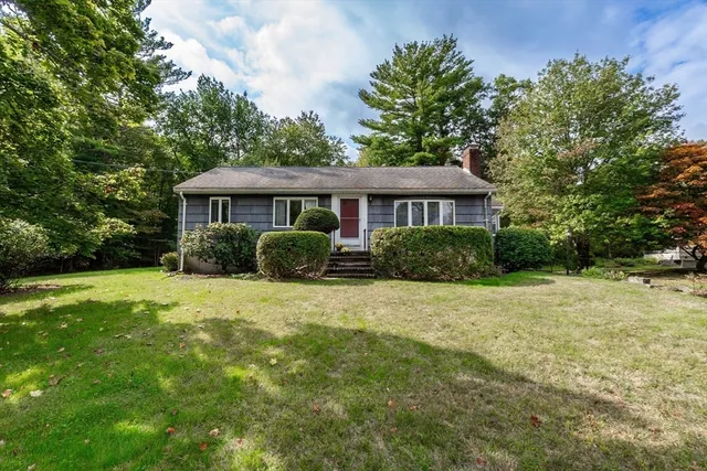 a front view of a house with a yard and trees