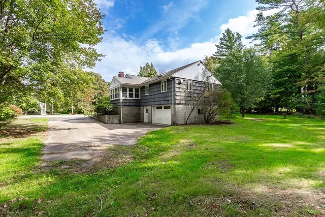 a view of a big house with a big yard and large trees