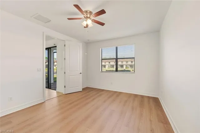 an empty room with wooden floor and a ceiling fan
