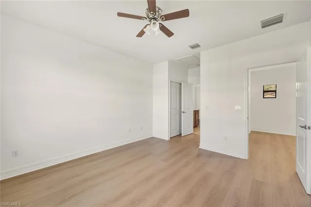 an empty room with wooden floor ceiling fan and windows