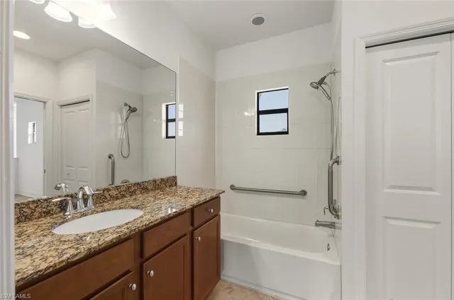 a bathroom with a granite countertop sink a mirror and a bathtub