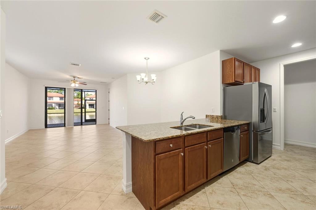 7770 Bristol Circle Naples, FL 34120 - Photo 36 of 36 Kitchen featuring dark stone counters, pendant lighting, a peninsula, light tile patterned floors, and open floor plan