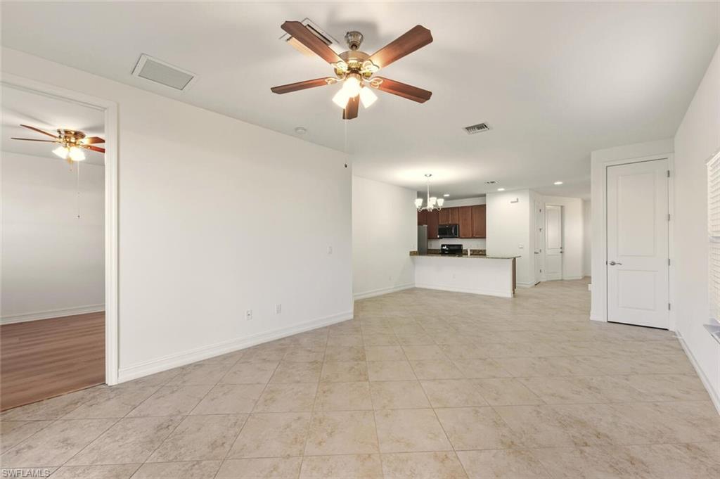 7770 Bristol Circle Naples, FL 34120 - Photo 4 of 36 Unfurnished living room with a ceiling fan, a chandelier, and light tile patterned flooring