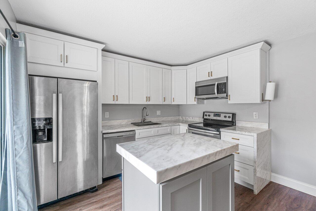 22172 Boca Rancho Drive, Unit D Boca Raton, FL 33428 - Photo 7 of 15 a kitchen with stainless steel appliances a stove refrigerator sink and cabinets