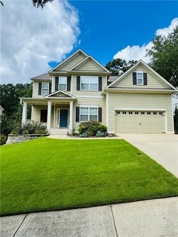 a view of a white house with a big yard and potted plants