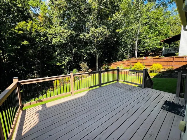 a view of swimming pool with wooden deck and large trees