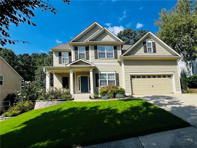 a front view of a house with a yard and green space