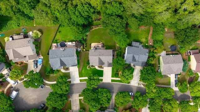 an aerial view of a house with outdoor space and trees all around