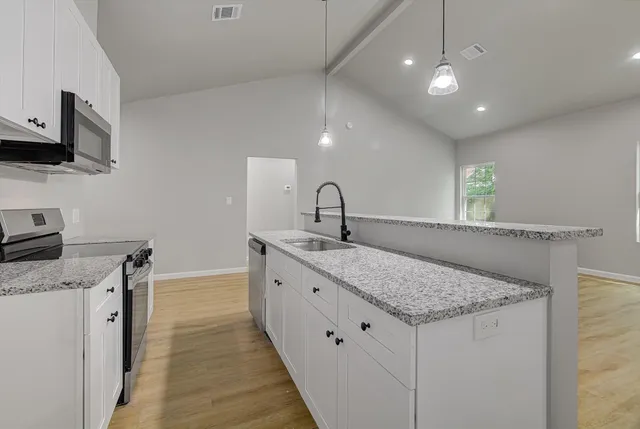 a kitchen with granite countertop kitchen island a sink stainless steel appliances and white cabinets