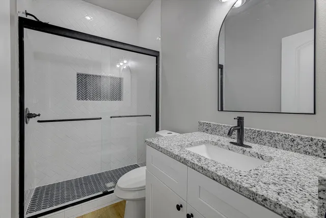 a bathroom with a granite countertop sink toilet and mirror