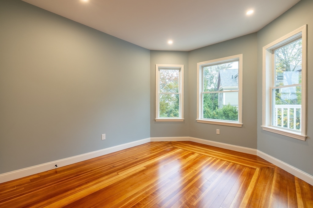 663 Columbia Road, Unit 1 Boston, MA 02125 - Photo 2 of 12 an empty room with wooden floor and windows