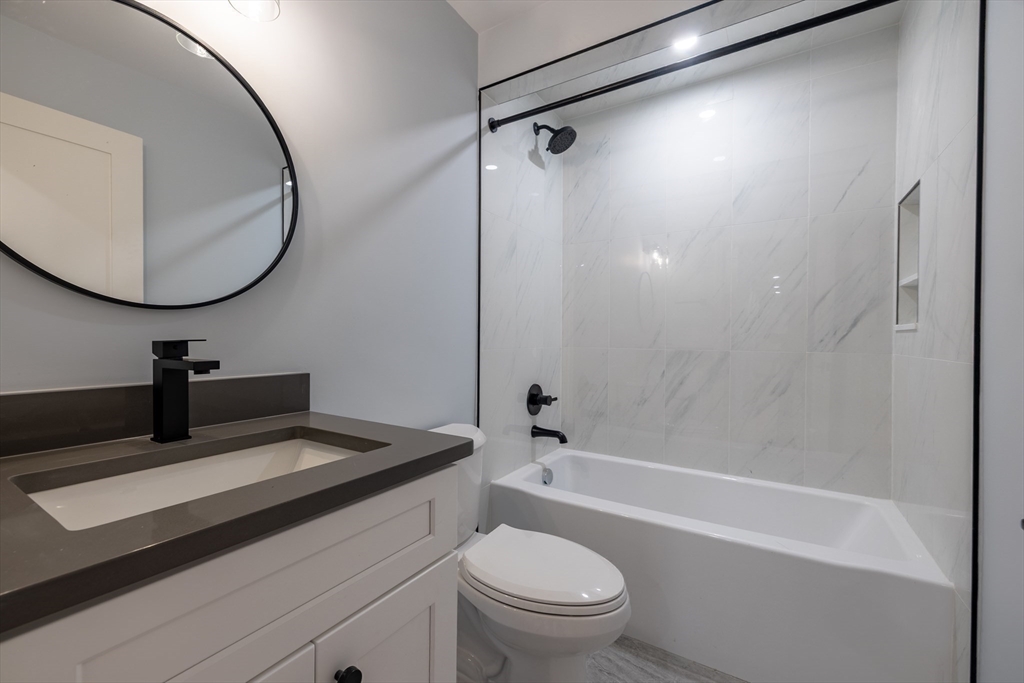 663 Columbia Road, Unit 1 Boston, MA 02125 - Photo 3 of 12 a bathroom with a sink a toilet and a mirror