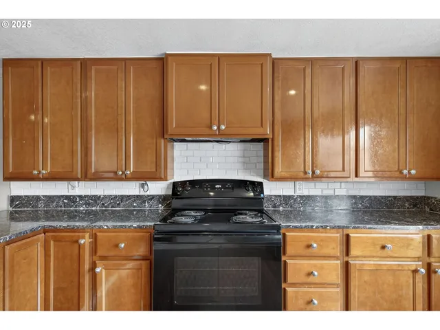 a kitchen with granite countertop wooden cabinets and a stove top oven