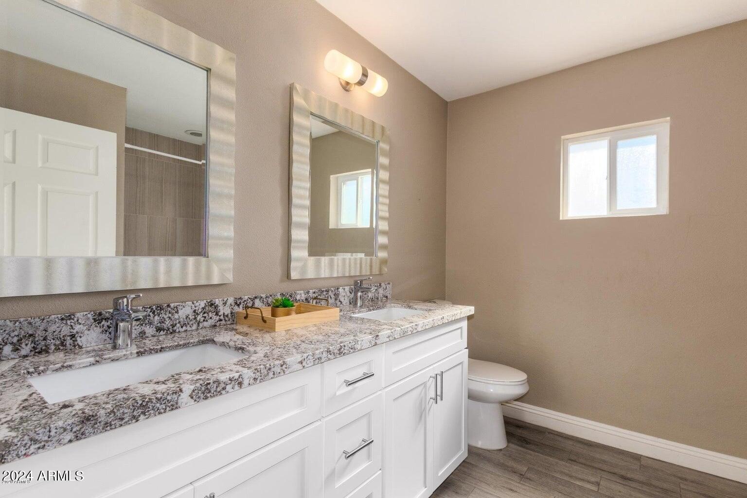 2350 North 55th Street Phoenix, AZ 85008 - Photo 14 of 20 a bathroom with a granite countertop sink a toilet and a mirror