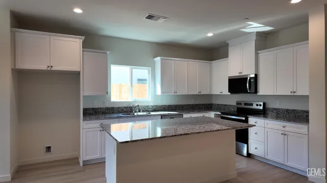 a kitchen with granite countertop a sink a stove and cabinets