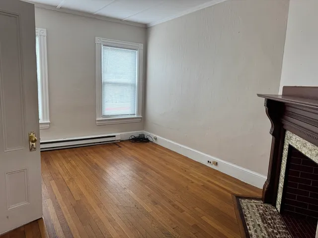 an empty room with a fireplace and wooden floor