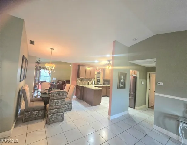 a dining room with furniture a chandelier and kitchen view