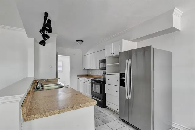 a kitchen with stainless steel appliances granite countertop a refrigerator a stove and a sink