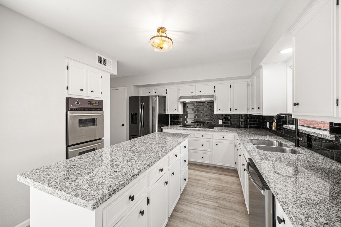 15686 Barkers Landing Road Houston, TX 77079 - Photo 13 of 32 Kitchen area offers a long central island w/ granite counters, double oven, eletric stove top, stainless steel refrigerator & updated Kitchen Faucet. Window looks out to back patio. Plenty of cabinet & counter space.