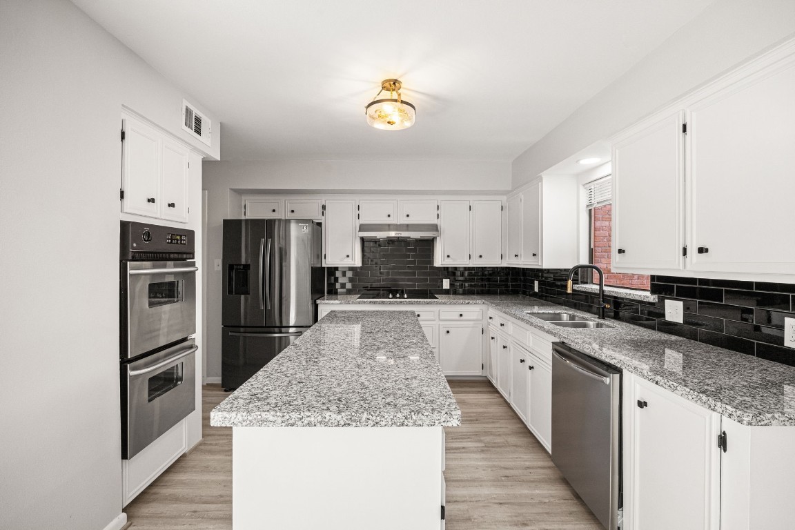 15686 Barkers Landing Road Houston, TX 77079 - Photo 15 of 32 Kitchen area offers a long central island w/ granite counters, double oven, eletric stove top, stainless steel refrigerator & updated Kitchen Faucet. Window looks out to back patio. Plenty of cabinet & counter space.