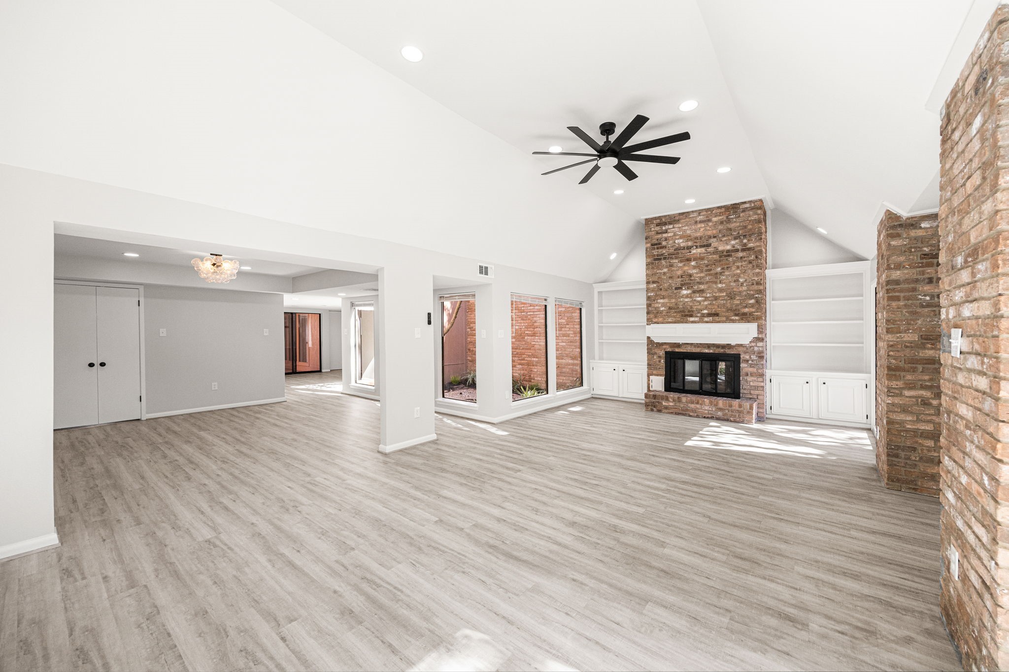 15686 Barkers Landing Road Houston, TX 77079 - Photo 8 of 32 an empty room with wooden floor a ceiling fan a fireplace and windows