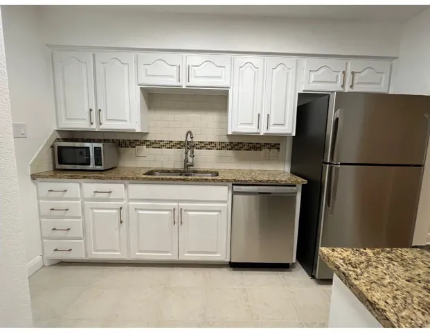 a kitchen with stainless steel appliances granite countertop a refrigerator sink and cabinets