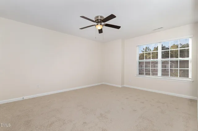 an empty room with window and ceiling fan