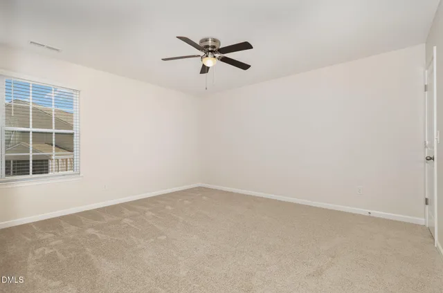 an empty room with a window and a ceiling fan